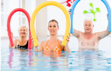 Monitor y pareja de personas mayores realizando ejercicios dentro del agua.