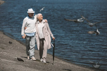 Pareja de personas mayores caminando por la playa 